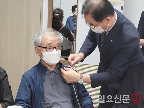 최재관 지역위원장이 민주고문 위촉식에서 민주당 배지를 달아주고 있다.