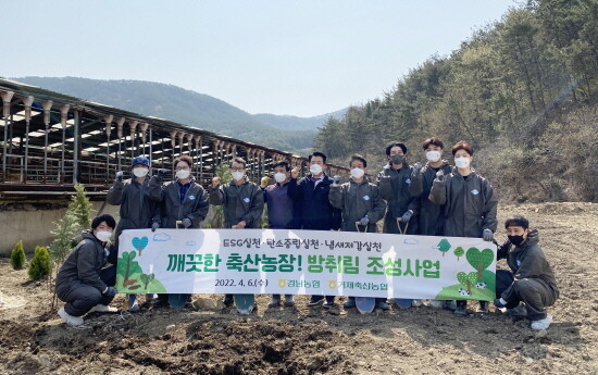 경남농협 및 거제축산농협 임직원들이 방취림을 식재하는 축산농가 앞에서 단체 기념사진을 촬영하고 있다. 사진=경남농협 제공