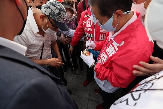 홍준표 대구시장 후보가 19일 오후 4시께 반월당역 현대백화점 앞에서 출정식을 가진 후 한 지지자가 건넨 금빛공에 사인을 해주고 있다. 사진=남경원 기자