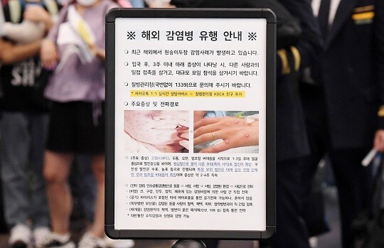 인천국제공항 제1터미널 입국장에 해외입국자들이 검역을 받기 위해 대기하는 가운데, 승객들 앞에 세워진 원숭이두창 관련 안내문. 사진=연합뉴스