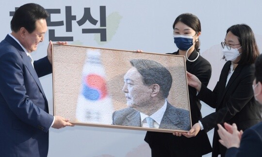 윤석열 당선인이 5월 6일 오후 서울 종로구 삼청동 대통령직인수위원회에서 열린 인수위 해단식에서 450여 명의 인수위관계자 사진으로 꾸며진 기념품을 전달받고 있다. 사진=인수위사진기자단