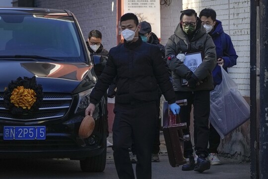 외신 보도에 따르면 베이징 등 중국 주요 도시에서 코로나19 확진자와 사망자가 급증하고 있다. 중국 베이징의 한 발열 진료소 밖에서 유족들이 영정 사진을 들고 영구차 옆을 지나고 있다. 사진=AP/연합뉴스