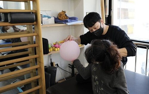 ㈜식스에프에서 중도중복 장애인이 전문가의 조력에 따라 분홍색 풍선에 손을 대며 움직이고 있다. 부드럽고 가벼운 밝은 색 풍선으로 장애인의 관심을 유도해 스스로 움직이게 돕는 것이다. 사진=남경원 기자