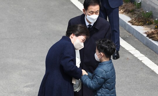 특별사면 후 병원에서 입원치료하다 퇴원한 박근혜 전 대통령이 2022년 3월 24일 대구시 달성군 사저에 도착해 동네 초등학생에게 환영 꽃다발을 받고 있다. 뒤에는 박 전 대통령의 최측근으로 알려진 유영하 변호사가 보좌하고 있다. 사진=임준선 기자