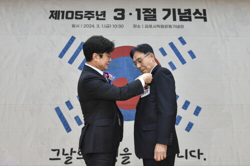 김병수 시장이 광복회원들을 대표하여 강성보 광복회장에게 직접 뱃지를 달아 주고 있다. 사진=김포시 제공