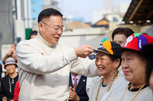 김재욱 군수가 칠곡할매래퍼 그룹 텃밭 왕언니 창단식에 참석해 할머니들에게 힙합 그룹을 상징하는 모자를 씌워주며 격려하고 있다. 사진=칠곡군 제공