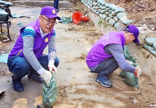 양평 미소지음 봉사단원인 이종인 전 도의원(왼쪽)이 침수 예방을 위해 모래주머니를 쌓고 있다. 사진=씨엘의집 제공