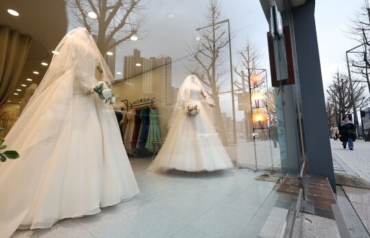 연간 혼인 건수가 3년 연속 20만 건을 밑도는 가운데 서울 마포구 아현동 웨딩거리에서 한 시민이 웨딩드레스 앞을 지나고 있다. 사진=연합뉴스