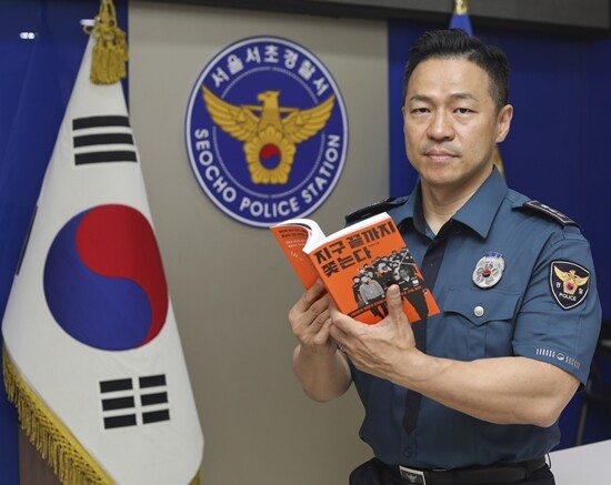인터폴 최장수 계장 전재홍 경정이 자신이 쓴 책 ‘지구 끝까지 쫓는다’를 들고 있다. 사진=박정훈 기자