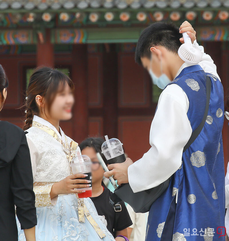 8일 오후 서울 경복궁을 찾은 관광객들이 휴대용 선풍기로 흐르는 땀을 말리고 있다. 사진=임준선 기자