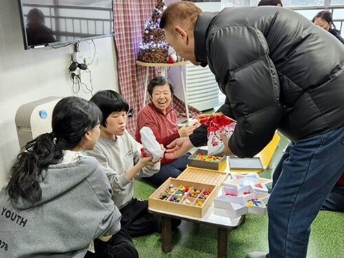 전국노점상총연합 중부지역 회원들이 성탄을 앞둔 20일 중증장애인 거주시설 씨엘의집 장애인들에게 크리스마스 선물을 선사하고 있다. 사진=씨엘의집 제공