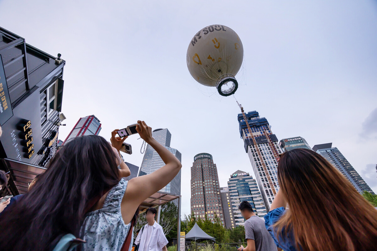 탑승을 기다리던 관광객이 여의도 상공에 떠오른 '서울달'을 휴대폰으로 찍고 있다. 사진=최준필 기자