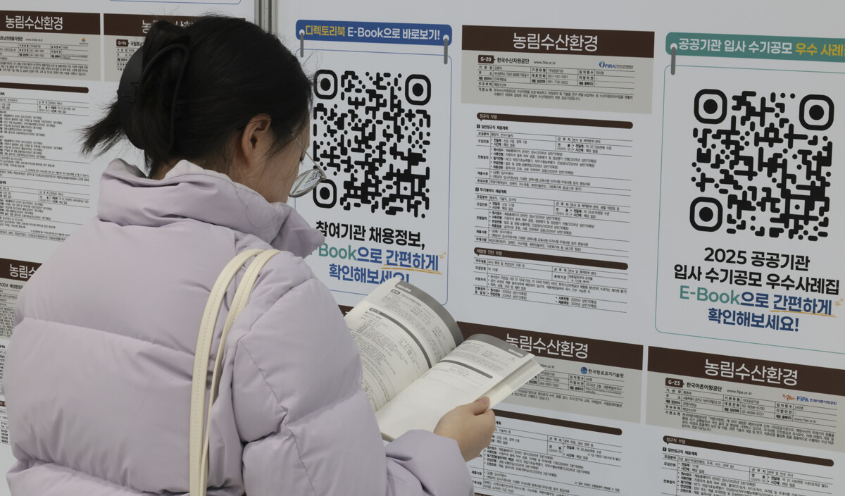 한 구직자가 취업 게시판과 자료집을 살펴보고 있다.