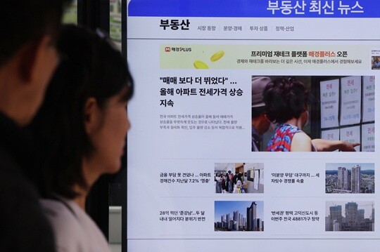 서울의 한 부동산중개업소 앞에 붙은 부동산 기사를 보는 시민들. 사진=연합뉴스